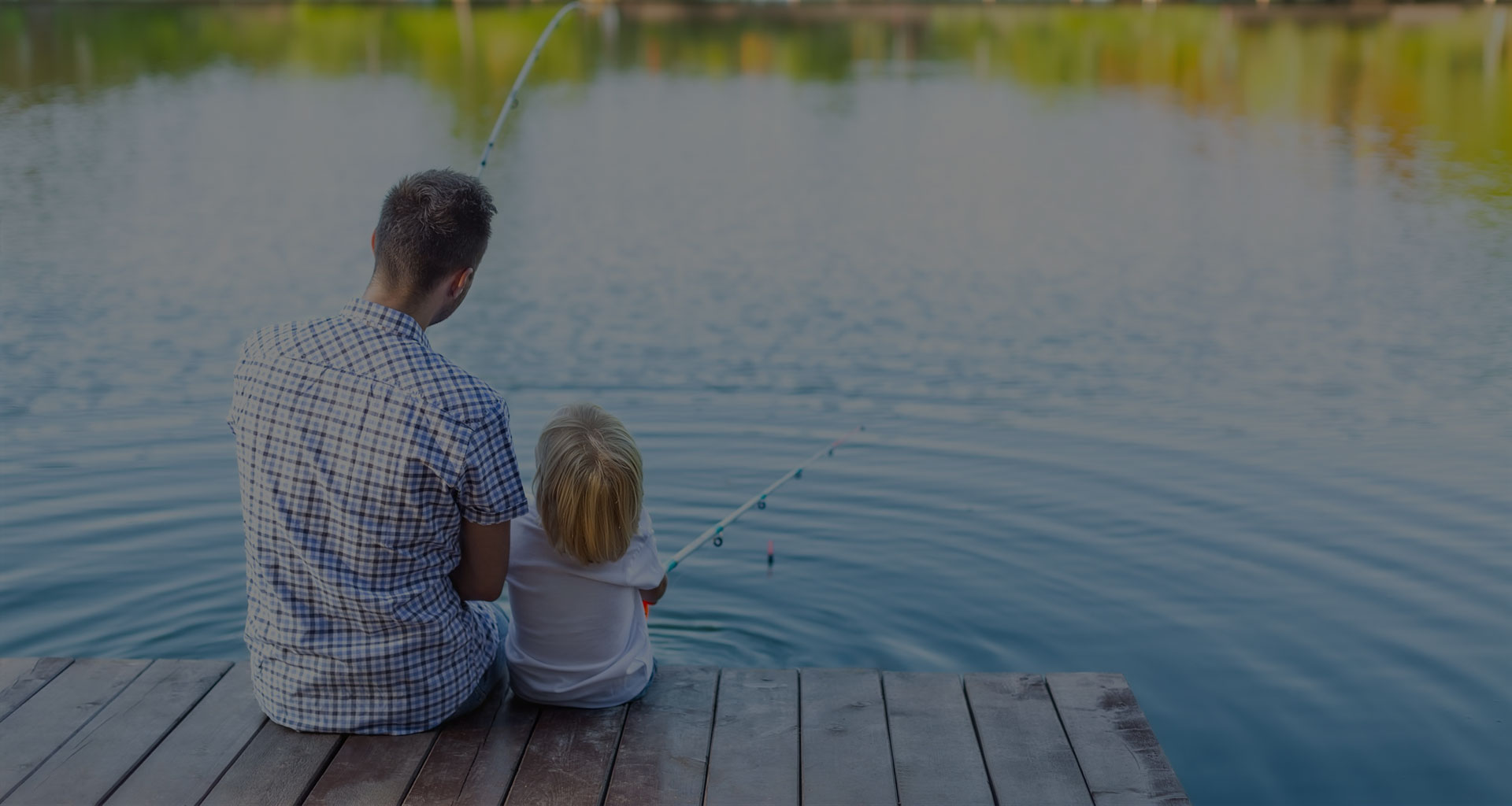 Father and child sitting on dock fishing on Lake Arbutus